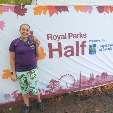 Me in running kit standing in front of Royal Parks Half branding with medal